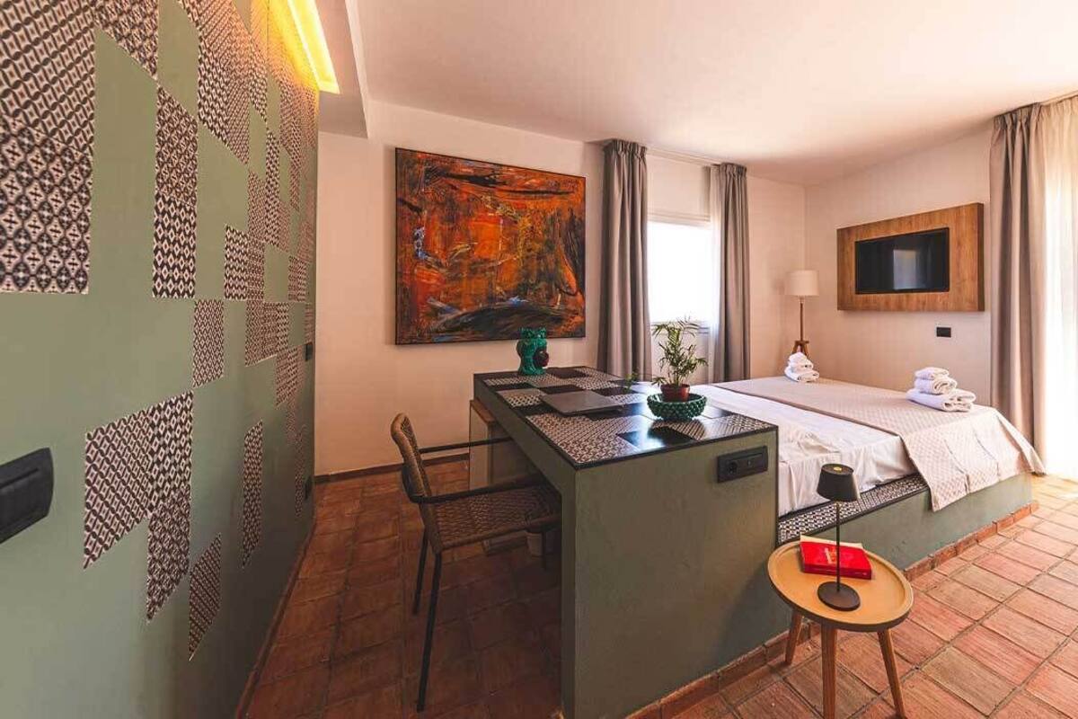 A hotel room with a bed, a desk, a chair, a TV, and a balcony with a view.