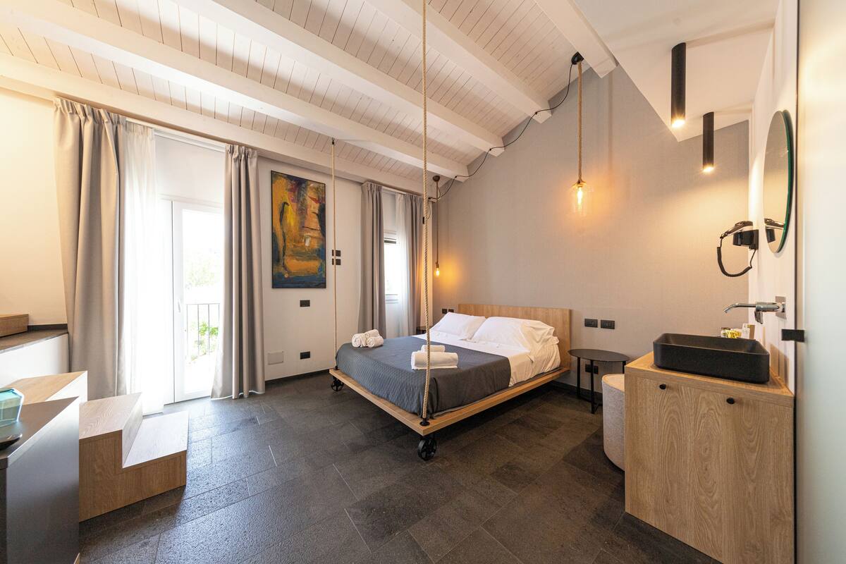 A modern hotel room with a bed, bedside table, and a wooden cabinet.
