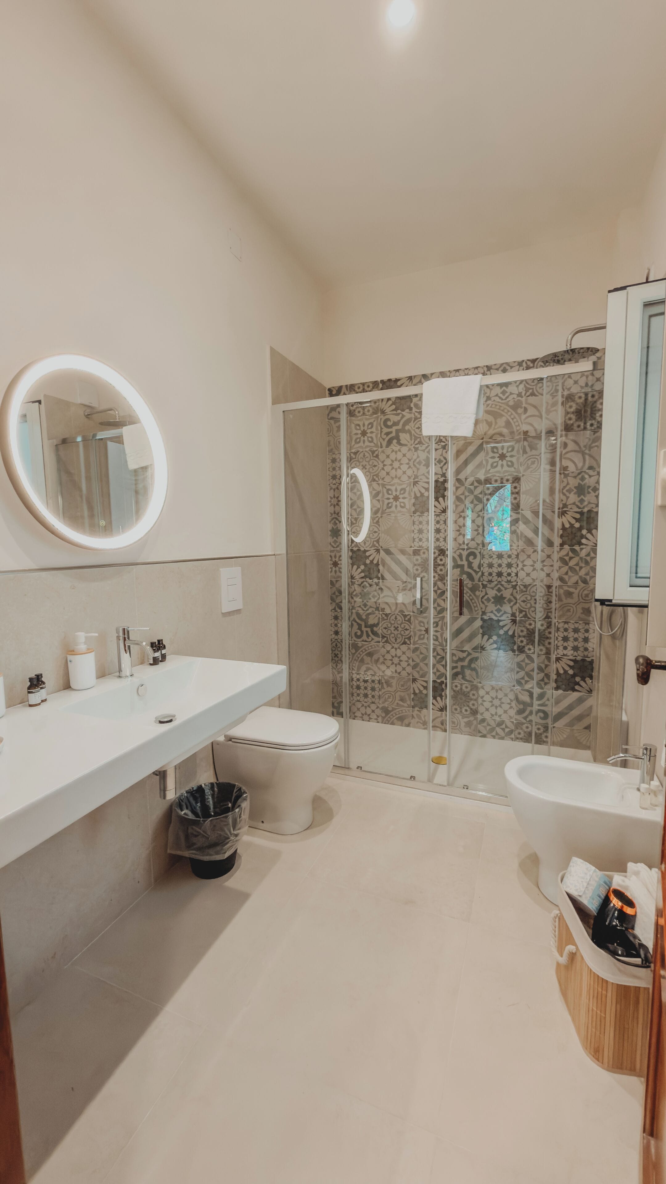 Un baño moderno con ducha, inodoro, bidé y un espejo grande.