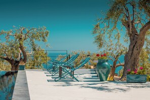 A terrace with lounge chairs, a pool, and potted plants. - Villa Totò Resort  (Cefalù)