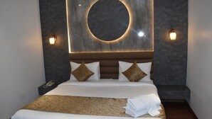 A modern hotel room with a large bed, a circular light fixture above the headboard, and two wall-mounted lights. - 3AG HOTEL & RESORT (Faizabad)