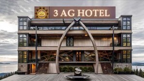 A modern 3 AG Hotel with a prominent sign, a unique architectural design featuring a central structure, and a view of the surrounding landscape. - 3AG HOTEL & RESORT (Faizabad)