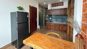 Una cocina compacta con refrigerador, armarios de madera y un comedor con mesa.