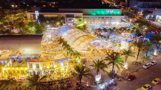 An aerial view of a bustling urban area with a prominent building featuring a large glass facade and a sign that reads "NEMO". - CHAMECO ART Boutique Home Danang (Da Nang)