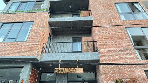 Un edificio de varios pisos con un llamativo letrero de 'CHAMECO art' en la entrada.