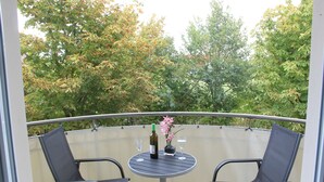 A balcony with two chairs and a table, a bottle of wine, and a vase with flowers. - 4-star apartment near the beach with two balconies (Ostseebad Boltenhagen)