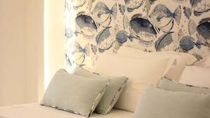 A bed with a patterned headboard, pillows, and a bedspread. - MARE Tropea Boutique Rooms (Tropea)