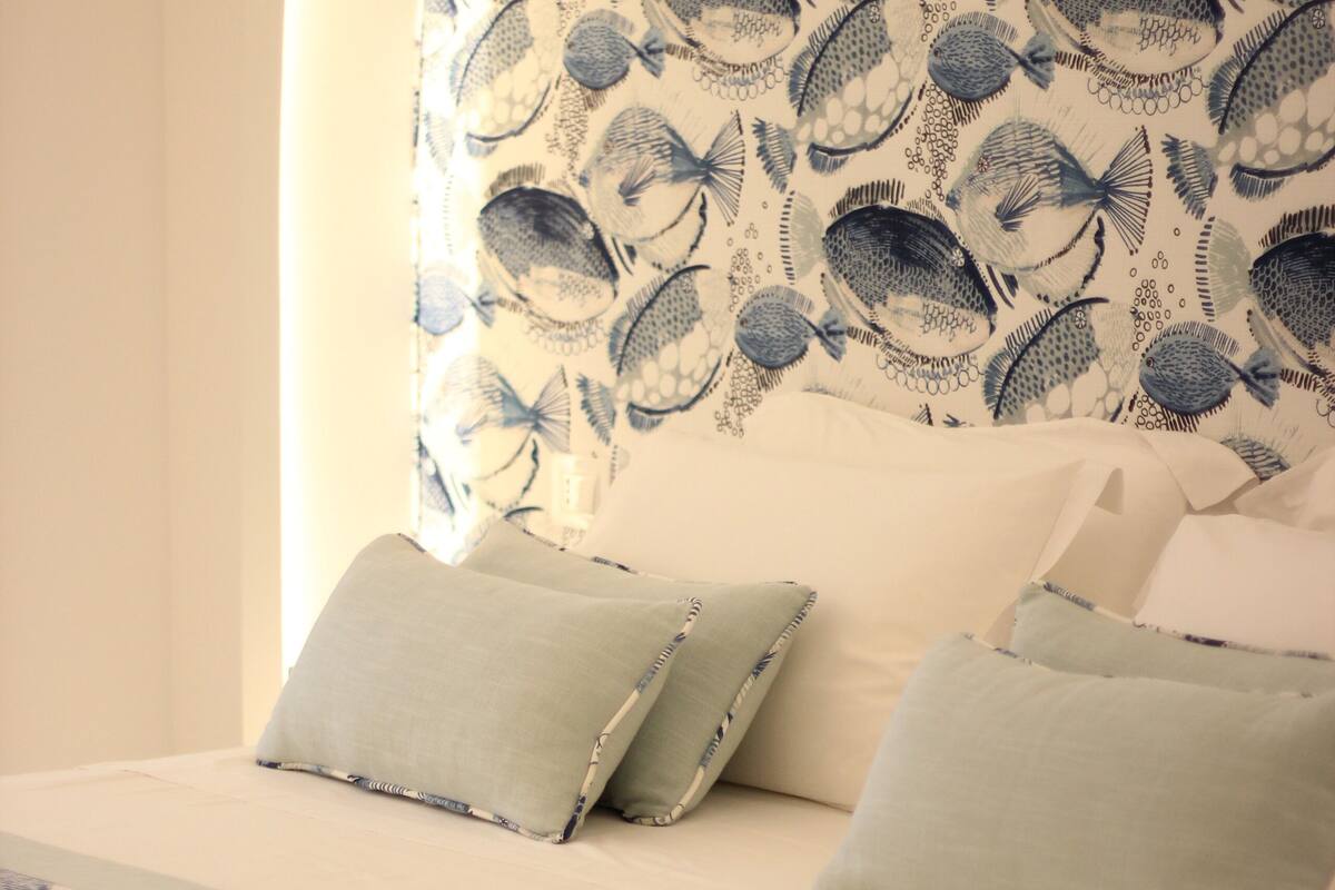 A bed with a patterned headboard, pillows, and a bedspread.