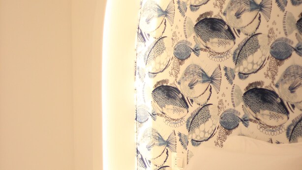 A bedroom with a bed, pillows, and a wall with a fish pattern. - MARE Tropea Boutique Rooms (Tropea)