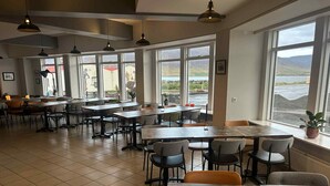 Un amplio comedor con ventanas grandes, piso de baldosas y mobiliario moderno.
