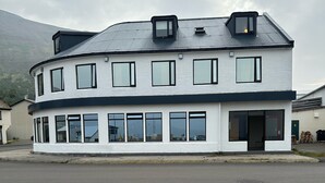 Un edificio de dos pisos con techo plano, ventanas grandes y una puerta con paneles de vidrio.