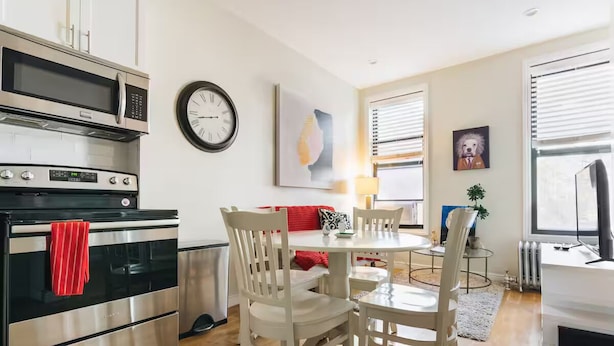 A modern kitchen with a built-in oven, microwave, and a dining area with a round table and white chairs.