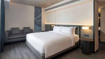 Una habitación de hotel moderna con una cama grande, un sofá y una pequeña mesa.