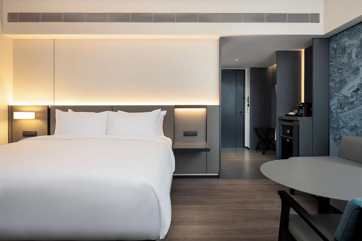 Une chambre d’hôtel moderne dotée d’un grand lit, de tables de chevet, d’un bureau et d’un coin salon.