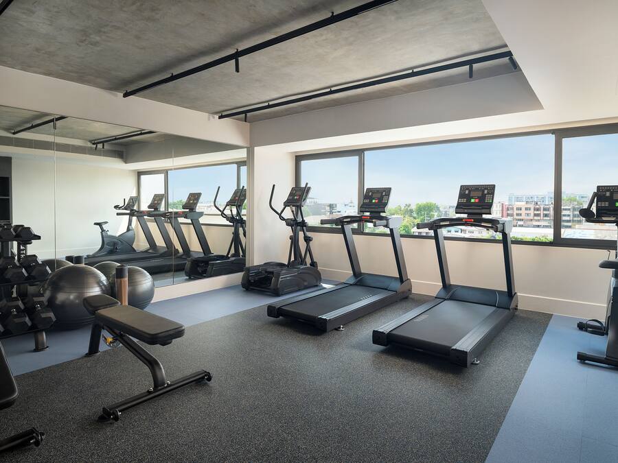 Een moderne sportschool met loopbanden, gewichten en fitnessballen.