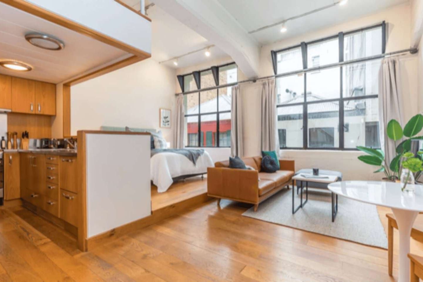 Ein modernes Interieur mit Küche, einem Bett, einer Couch und einem Essbereich.