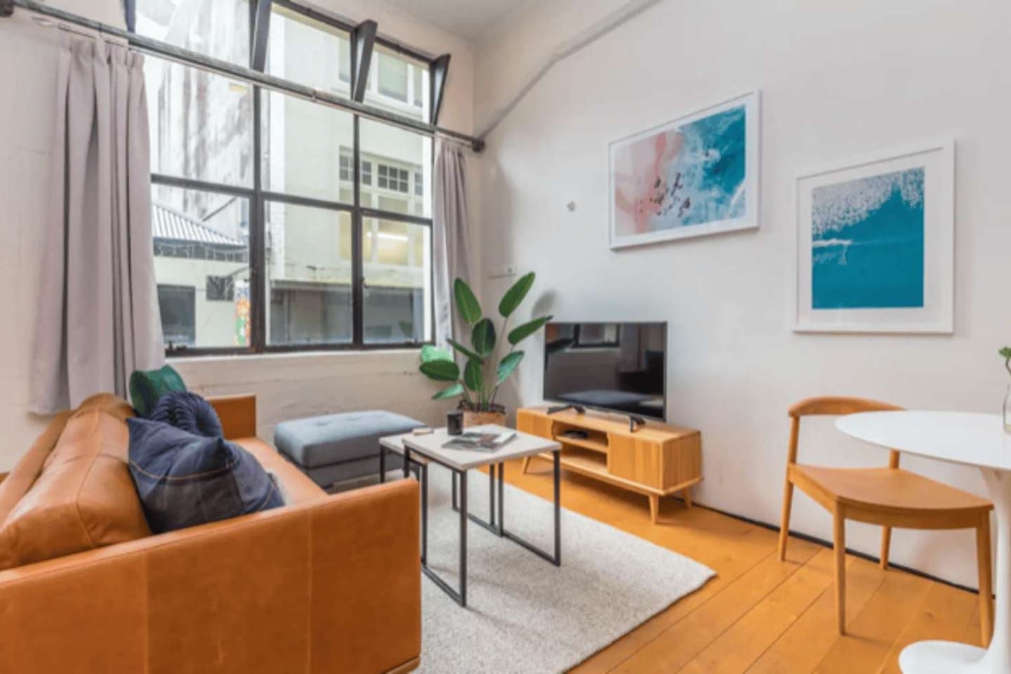 A modern living room with a sofa, a coffee table, a TV, and a dining area.