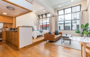 A modern interior with a kitchen, dining area, and a bedroom with a large window. - Central stylish studio in CBD by Zodiak Stays (Auckland)