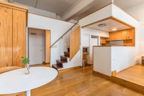A modern interior with a staircase, wooden flooring, a white table, and a small plant. - Stylish Studio in Centre by Zodiak Stay (Auckland)