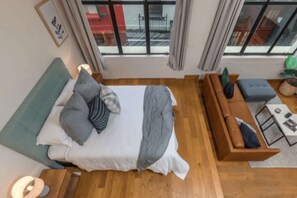 Quarto moderno com uma cama, um sofá e vista para o exterior.