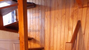 A wooden staircase with multiple steps leading upwards, against a wooden wall.
