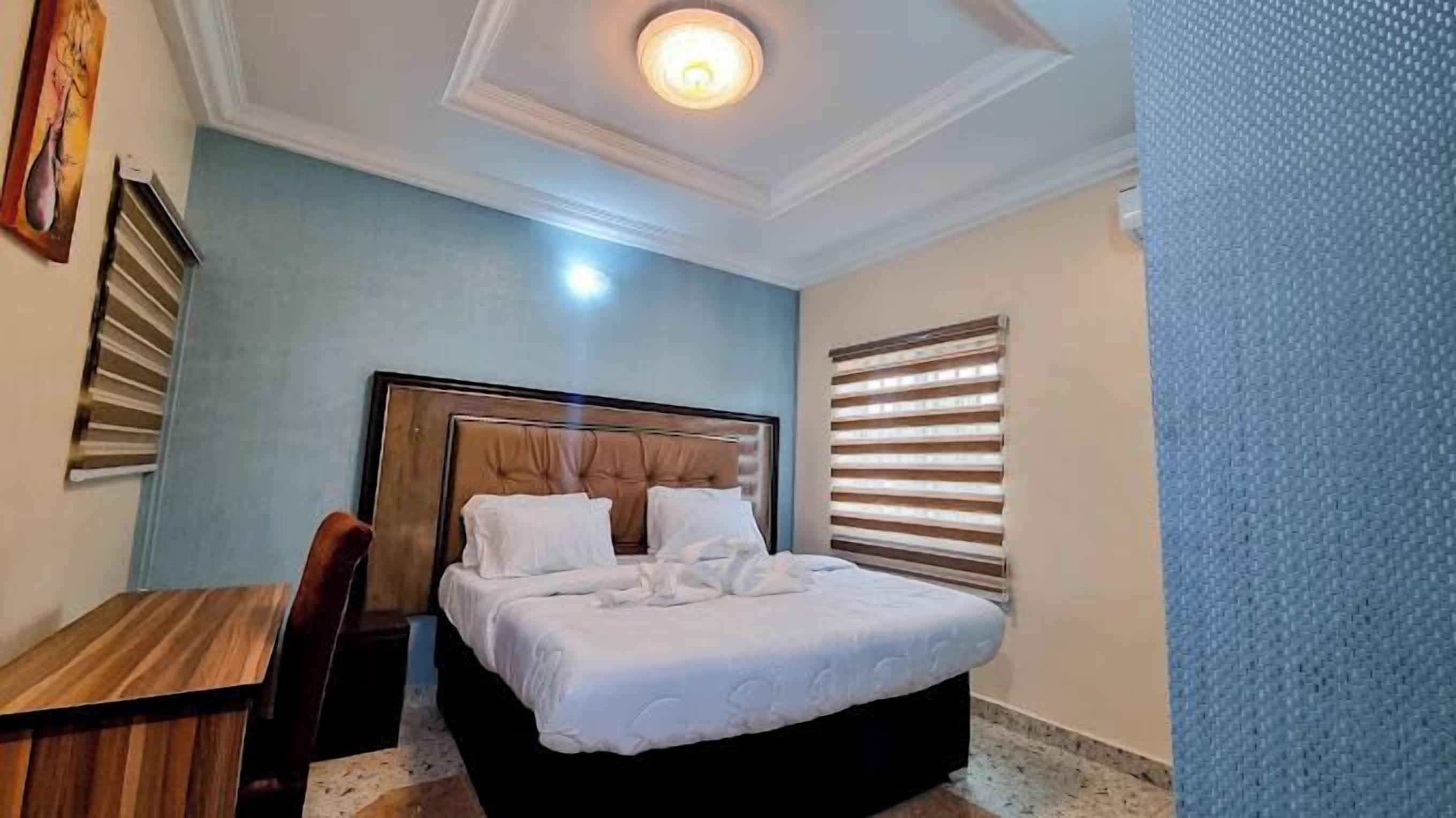 A bedroom with a bed, a desk, and a chair.