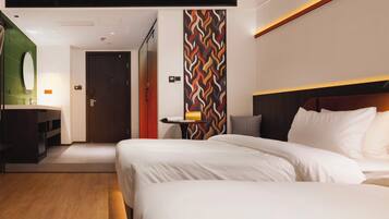 A hotel room with a large bed, a bedside table, a mirror, and a wall with a geometric pattern.