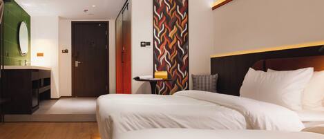 Habitación de hotel con una cama grande, una mesita de noche, un espejo y una pared con diseño geométrico.