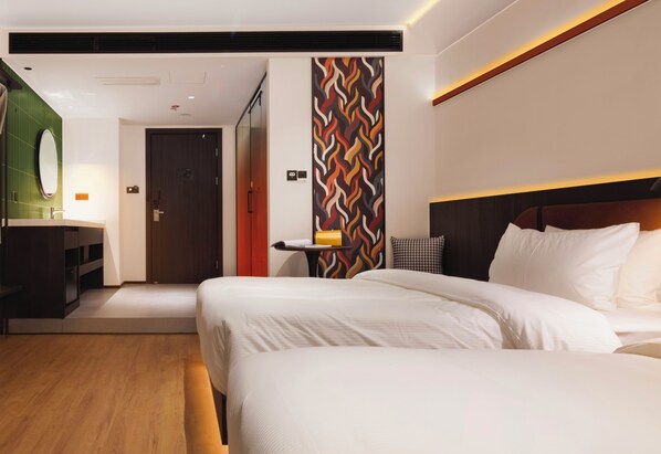 Habitación de hotel con una cama grande, una mesita de noche, un espejo y una pared con diseño geométrico.