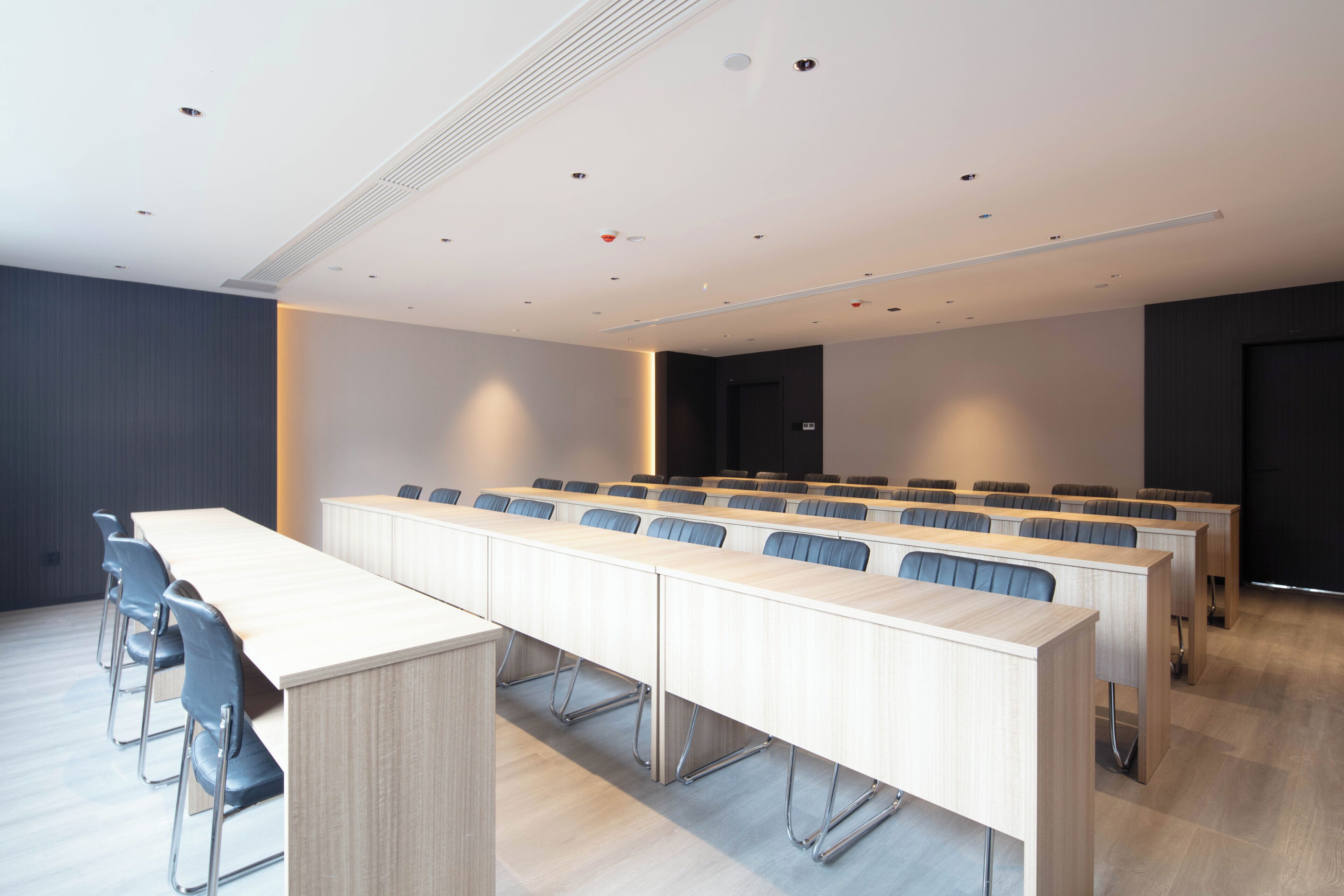 A conference room with a long table, several chairs, and a dark-colored door in the background.