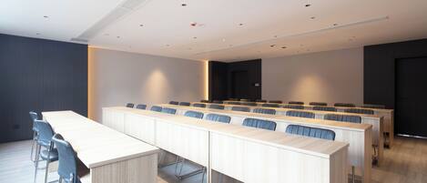 A conference room with a long table, several chairs, and a dark-colored door in the background.