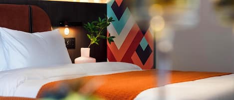 A hotel room with a bed, a nightstand, a lamp, and a wall with a geometric pattern.