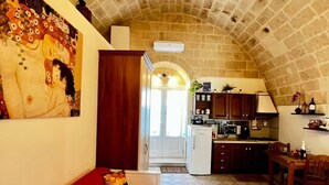 A cozy, compact living space with a kitchen area, featuring a vaulted ceiling and a red sofa. - In the heart of the Sassi of Matera at 500 mt. from the historic center, apartment Deluxe (Matera)