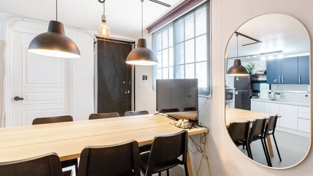 A modern kitchen with a large island, a dining area with a long table and chairs, and a large mirror on the wall. - Stylish Itaewon Getaway | Spacious Living, Projector, 4 Beds, 5 min to Station (Seoul)