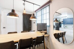 Una cocina moderna con una isla grande, un comedor con una mesa larga y sillas, y un espejo grande en la pared.
