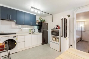 Een kleine keuken met een wasmachine, een magnetron en een koelkast.