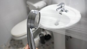 A hand holding a showerhead with water flowing from it. - Stylish Itaewon Getaway | Spacious Living, Projector, 4 Beds, 5 min to Station (Seoul)
