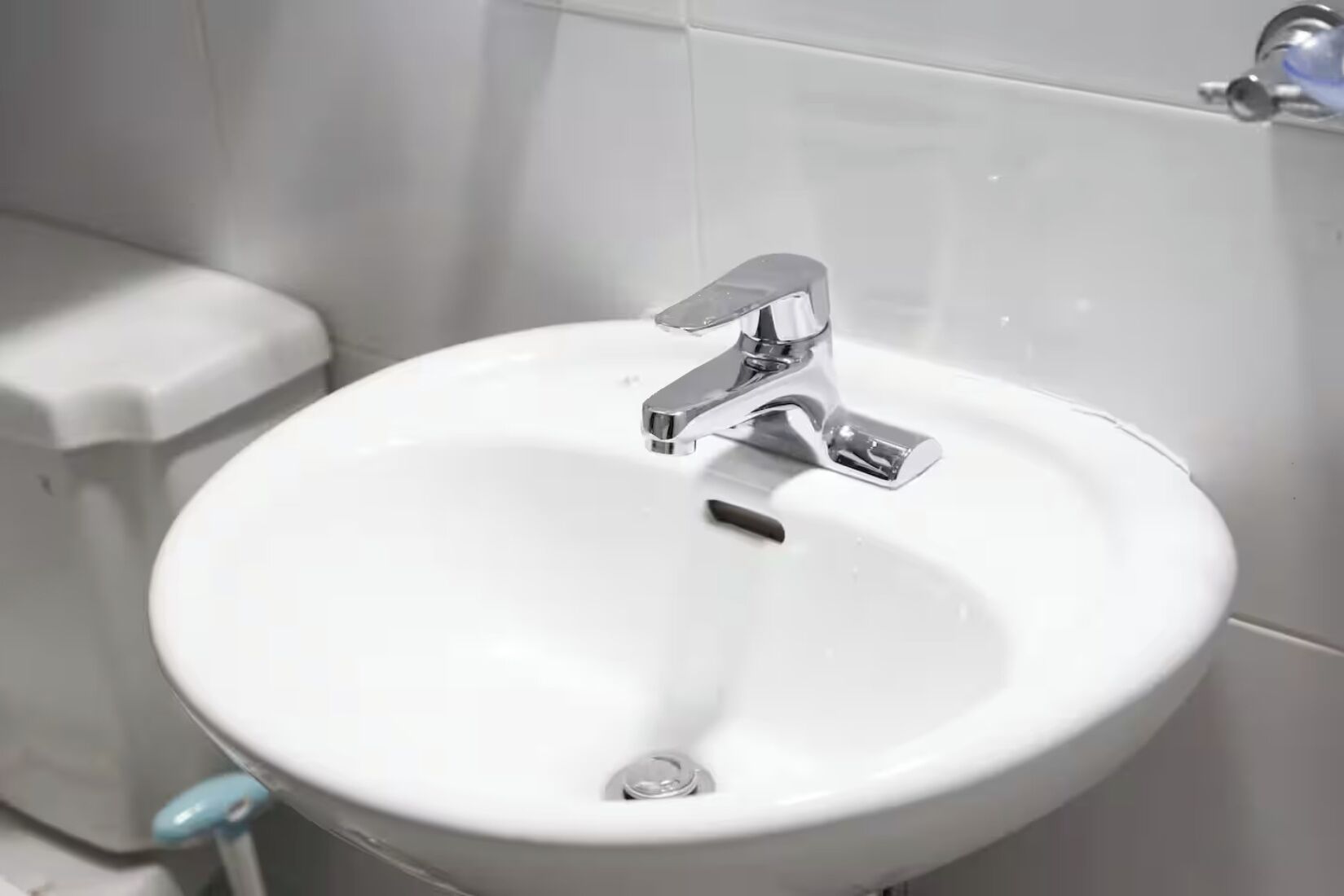 Une salle de bain avec un lavabo blanc, un robinet chromé et des toilettes.