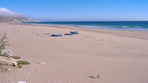 A beach with several boats on the sand and a clear sky.