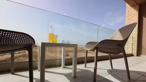 A balcony with two chairs and a table, a bottle of orange juice, and a glass of water.