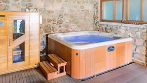 Una sauna in legno con pareti in pietra, una panca di legno e una finestra con vetro smerigliato.