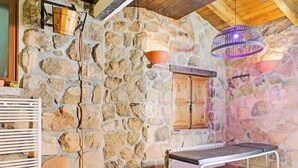 Una stanza con pareti in pietra, una panca, un soffitto in legno e un lampadario.