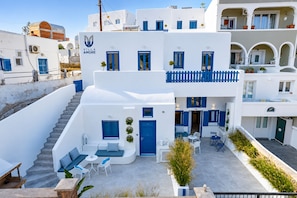 A white building with blue accents, a staircase, outdoor seating, and a sign that reads 'Villa Amore'. - Amore Villa (Santorini)