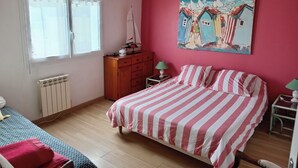 Ein Schlafzimmer mit Bett, Schminktisch, Heizkörper, Fenster und einem Bild an der Wand.