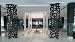 A spacious lobby with a marble floor, a central fountain, and decorative black panels. - One Resort Premium  (Hammamet)