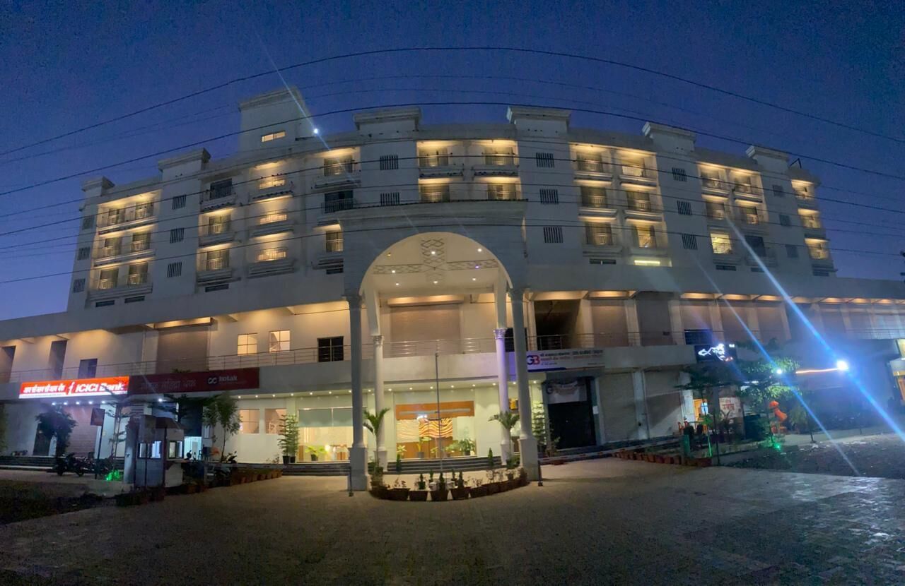 A multi-story hotel with a central entrance, a bank on the ground floor, and a well-lit facade.