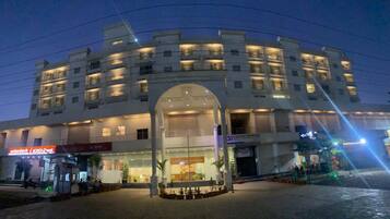 A multi-story hotel with a central entrance, a bank on the ground floor, and a well-lit facade.