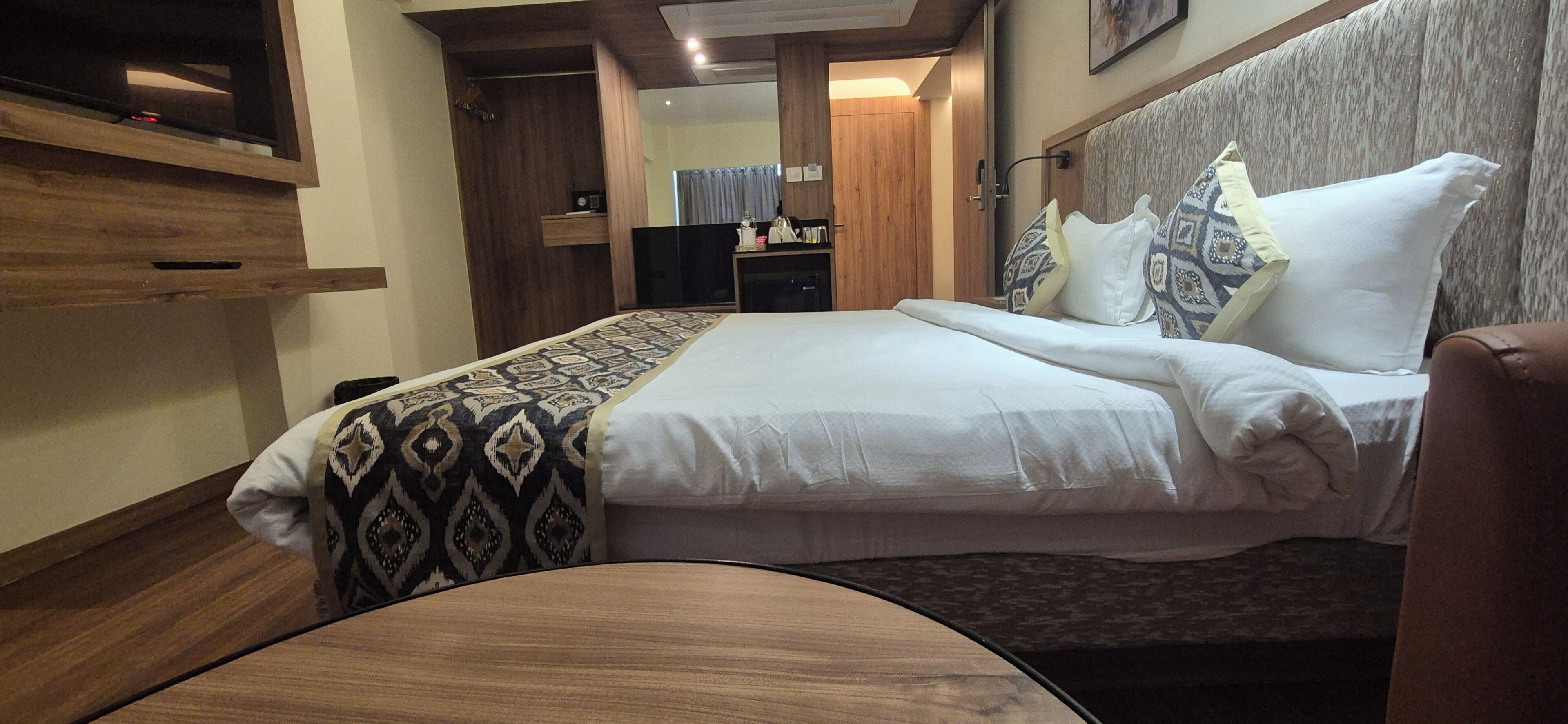 A hotel room with a bed, a bedside table, a wardrobe, and a television.