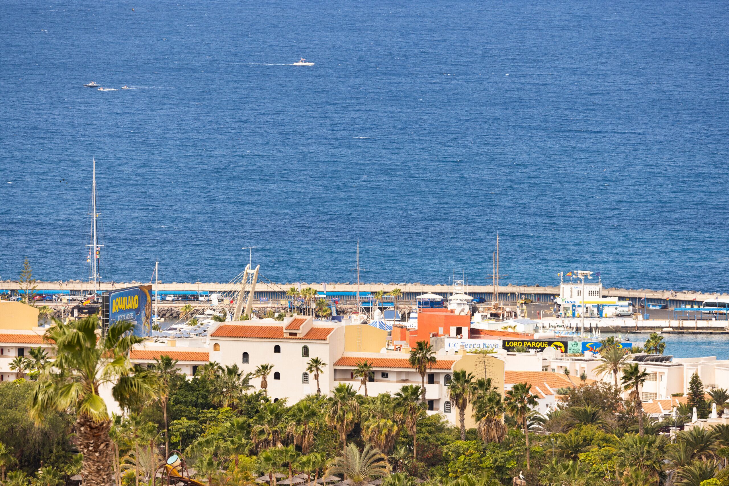 Un pueblo costero con edificios, un puerto deportivo y barcos.