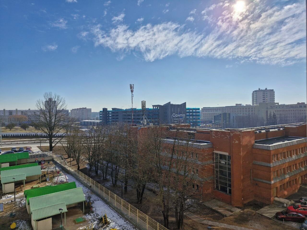 A view of a cityscape with multiple buildings, including a prominent red brick building and a modern high-rise.